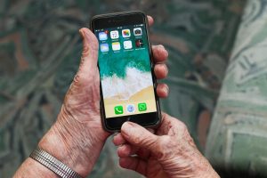 fotografia: spracowane ręce trzymają telefon komórkowy